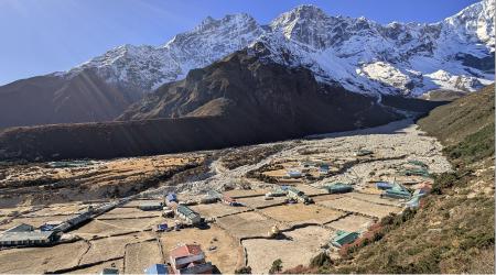 The village of Thame, sitting in an opening between cliifs. White, snowcapped mountains cover the background.