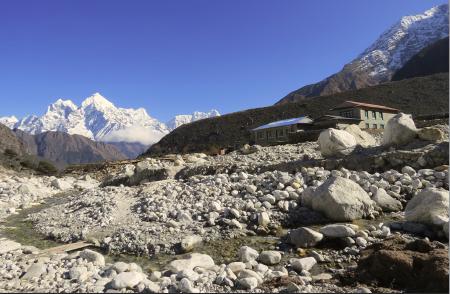 The building of Hotel Thame View sits in the rocky landscape. A snowcapped mountain peak peeks from the side.