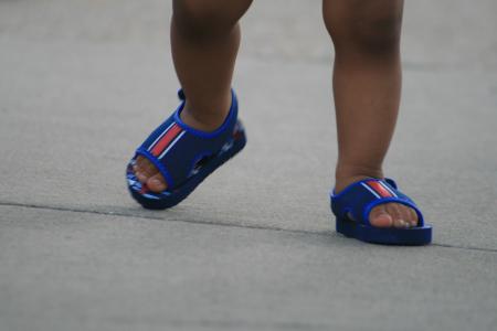 A pair of toddler feet walking on pavement